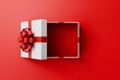 © PW.Stocker - Blank white rectangle gift box mock up open or top view of white present box product display showcase frame tied with red ribbon bow resting on a vibrant red background.