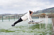© Мар'ян Філь - A woman in a white hoodie, gloves, and earmuffs trains a push-up on a  wooden benches on frosted field. This athletic outdoor scene highlights fitness, perseverance, and seasonal training