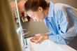 © teksomolika - Caucasian woman gently cleansing her face in soft warm light