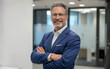 © Tmack - Confident professional businessman posing in modern corporate office environment