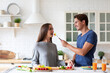 © BestForYou - Smiling man in a blue shirt is sitting at a kitchen table with a woman in a gray shirt. Happy expression.