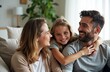 © starush - Family laughing together on couch with daughter embracing both parents
