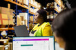 © DC Studio - Black worker reviewing products and organizing parcels on laptop in a startup warehouse. Storage racks full of merchandise and tech systems tracking deliveries, shipping in-house.