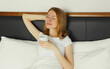 © rohappy - Happy smiling young woman enjoying with cup of hot coffee lying on bed at home
