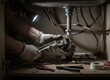 © Rudi - Plumber Wearing Work Gloves Uses Adjustable Wrench To Fix Under Sink Pipes With Flashlight Illuminating Dark Cabinet With Tools Scattered On Floor