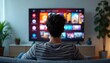 © Viktor - Young man sits on couch watching smart tv interface with movie posters. Male viewer browses content in living room, chooses show for relaxation and entertainment.
