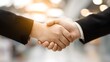 © kirania - Two individuals firmly grasp hands in a gesture symbolizing agreement or partnership.