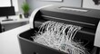 © Khlaing - A black and white shredder machine with shredded paper coming out.