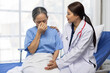 © Wasan - Young female doctor comforting a sad senior patient sitting on a hospital bed, expressing empathy and compassion while providing support during a difficult time of illness and grief.