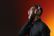 © SHOTPRIME STUDIO - Young Black man enjoying music with headphones, expressing joy and passion, wearing a black turtleneck against a vibrant gradient background