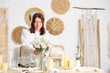 © Pixel-Shot - Pretty young woman serving table with beautiful flowers in dining room