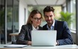 © Michael - Two business people using a laptop together in an office. High quality