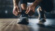© luzaein - Close-up shot of someone tying athletic shoes on a wooden floor