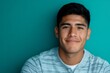 © Татьяна Евдокимова - Young Hispanic man feeling confident and happy, wearing casual clothes against a teal background, looking at camera
