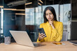 © Tetiana - Worried young Muslim businesswoman sitting at a desk in the office and looking at her mobile phone screen in frustration