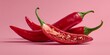 © Yuliia - Fresh red chili peppers with green stems on pink background, spicy hot peppers for cooking and culinary use in kitchen recipes and food preparation.