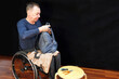 © Alex - A man in a wheelchair holds a backpack in his hands