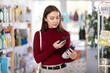 © JackF - Young woman buyer scanning qr code for cleaning spray in household chemicals store