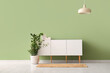 © Pixel-Shot - Modern chest of drawers with houseplant and lamp near green wall in room