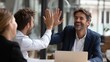 © Dao - Successful business people giving each other a high five in a meeting. Two young business professionals celebrating teamwork in an office.