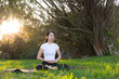 © leungchopan - Young woman doing calm meditation in green park