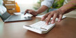 © Natee Meepian - Calculating Finances: Individual using calculator and laptop for budgeting