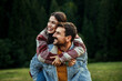 © La Famiglia - Smiling couple enjoying piggyback ride outdoors in nature