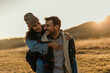 © La Famiglia - Happy couple enjoying piggyback ride outdoors during sunset