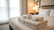 © daffagladius - Freshly Folded White Towels Placed on Bed in Bright Hotel Room Interior
