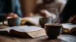 © andyaziz6 - A bible with aged, textured pages, open on a wooden table alongside steaming coffee cups, creating a warm, inviting atmosphere.