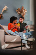 © Jose Calsina - Joyful couple sharing a delightful moment while using their smartphones together on a comfortable couch at home, engaged in a fun conversation and enjoying each other's company.
