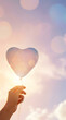 © Marcelino Victor M - Hand holding heart shape against soft pastel sky with bokeh light