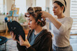 © qunica.com - A stylist works on a womans hair with curlers in a comfortable home environment, creating a relaxed, personal beauty moment with soft light and a warm atmosphere.