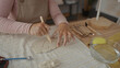 © Krakenimages.com - Woman uses bare hands and wooden tool to carve clay slab in pottery studio; creativity focus patience craftsmanship.