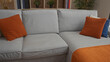 © Krakenimages.com - Soft grey sofa with orange cushion and matching textured throw in spacious building flanked by wooden bookshelf; serenity.