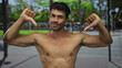 © Krakenimages.com - Shirtless young hispanic man bare chest shows dual thumbs down gesture on crowded street; disapproval.
