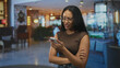 © Krakenimages.com - Woman reading phone with frown and crossed arms in modern building lobby, wearing glasses and casual top; frustration message problem.