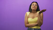 © Krakenimages.com - Woman wearing glasses and yellow top, hand on chin with arms crossed in studio purple backdrop; thoughtful doubt decision.