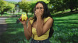 © Krakenimages.com - Young hispanic brunette woman wearing yellow top holding yellow piggybank pinches her nose in leafy forest; financial anxiety.