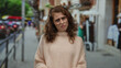 © Krakenimages.com - Woman expressing frustration on a busy city street wearing a cozy sweater as people and traffic blur in the background, capturing urban emotion and outdoor lifestyle.