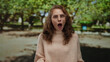 © Krakenimages.com - Woman in glasses expressing surprise while gesturing in an outdoor park setting with green foliage visible in the background.