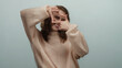 © Krakenimages.com - Woman framing an imaginary photo with hands in a cozy sweater against a plain background, expressing creativity and playfulness with a fun gesture.