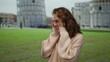 © Krakenimages.com - Young woman smiling near pisa tower in italy, wearing glasses and sweater on a bright outdoor day, capturing european architecture and joyful travel ambiance.