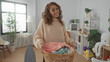 © Krakenimages.com - Woman smiling in bright laundry room holding a wicker basket of folded clothes showing domestic chores at home.