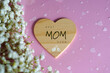 © Inspiraciones - Best mom ever. Message written on a wooden heart against a pink background with white flowers