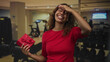 © Krakenimages.com - Woman holding red gift box with hand on forehead and smiling in building gymnasium; joy celebration gratitude.
