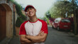© Krakenimages.com - Young man in a baseball uniform crosses arms with a confident smile on a city street, showcasing an outdoor urban setting and relaxed athletic style.