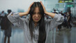 © Krakenimages.com - Frustrated woman in airport terminal with hands on head amidst busy crowd looking stressed and anxious in indoor travel environment.