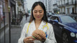 © Krakenimages.com - Woman doctor holding and pointing at a brain model with a stethoscope on a vibrant urban street backdrop, showcasing medical professionalism outdoors.
