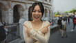 © Krakenimages.com - Young chinese woman smiling and pointing at both sides outside the roman coliseum, showcasing a lively outdoor scene in rome's iconic architecture.
